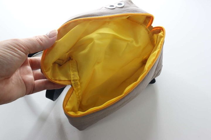 女性の手がギョロ目バッグを開け、内側の黄色い生地が見える。