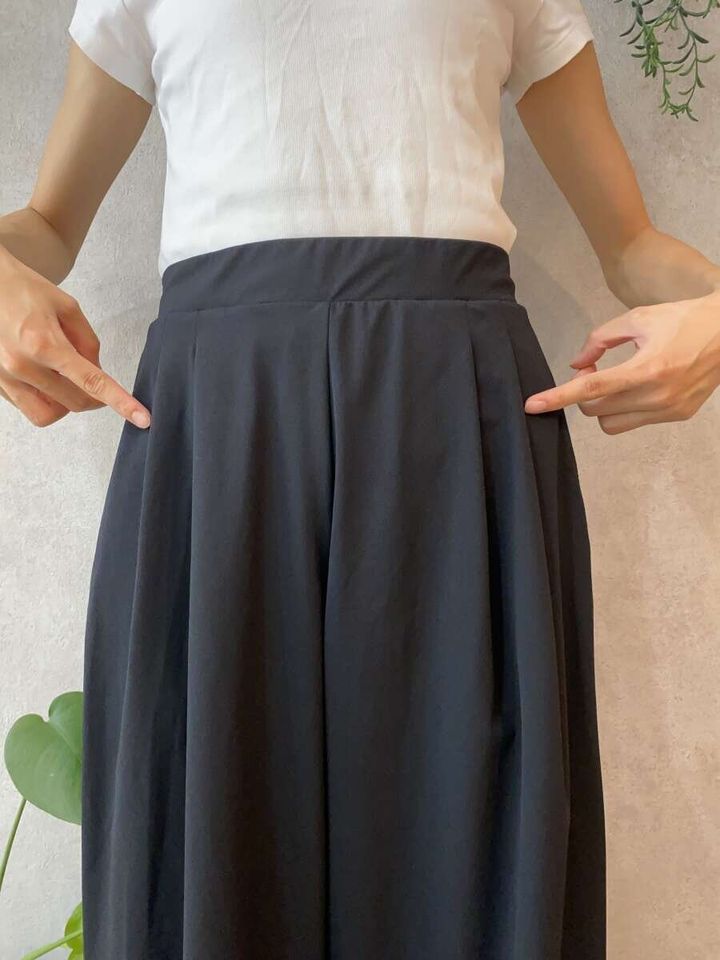 女性が黒いワイドパンツの腰部分のタックを指さしている