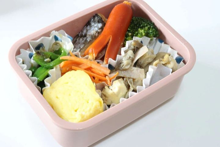 ピンク色の猫柄弁当箱に彩り豊かにおかずが詰まっている