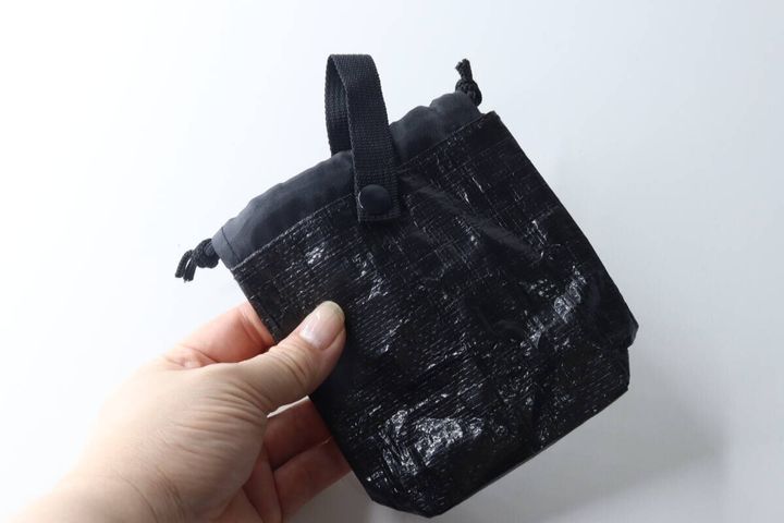 女性の手が黒い携帯ゴミ箱を掴んでサイズ感を示している