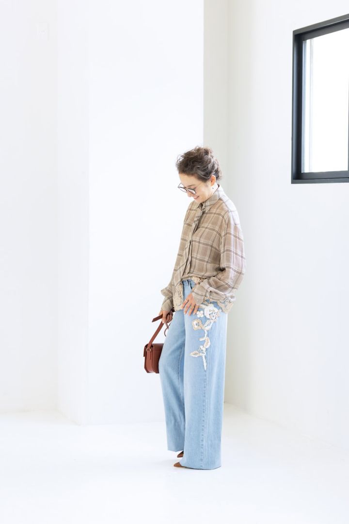 ネクタイつきブラウス¥159,500、デニムパンツ¥128,700／ともにエルマンノ フィレンツェ（ウールン商会）、メガネ¥49,500／アイヴァン（アイヴァン 東京ギャラリー）、ピアス¥286,000、薬指に重ねたリング（指先から）¥253,000、¥66,000、人さし指につけたリング¥572,000／すべてシンティランテ（イセタンサローネ東京ミッドタウン）、バッグ¥172,700／ピエール アルディ（ピエール アルディ 東京）、シューズ¥147,400／マローン・スリアーズ（メゾン・ディセット）