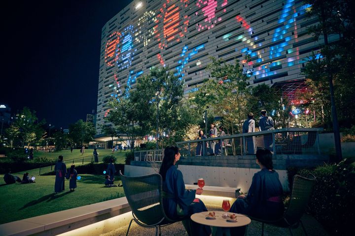 ライトアップされた建物を背景にドリンクを楽しむ「みやぐりん」の夜のイベント