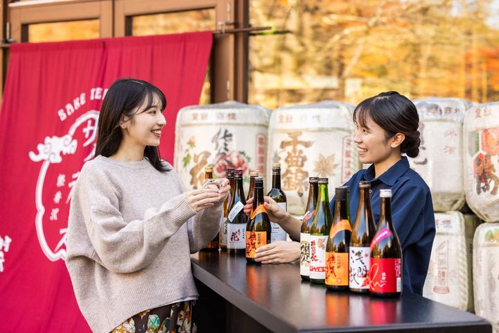 お猪口で日本酒を味わう来場者とスタッフ