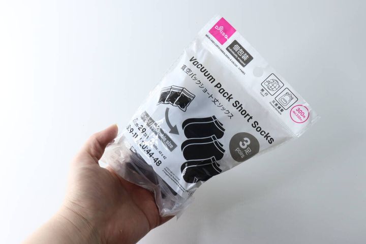 女性の手がダイソー真空パックショート丈ソックスのパッケージを持っている様子