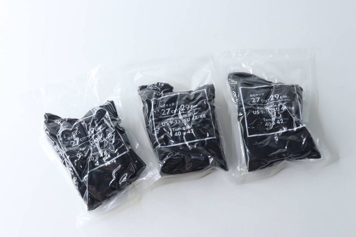 白い背景に並べられた個包装された黒いショート丈ソックス3足