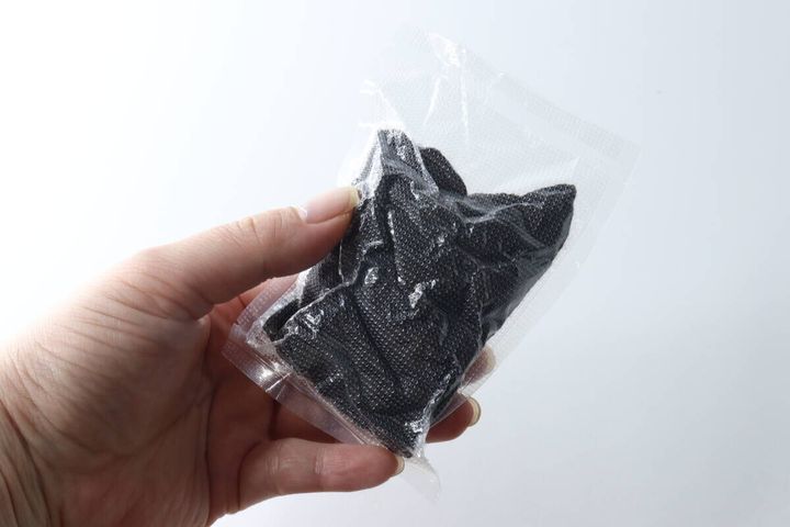 女性の手が個包装された黒いショート丈ソックスを1足持っている様子