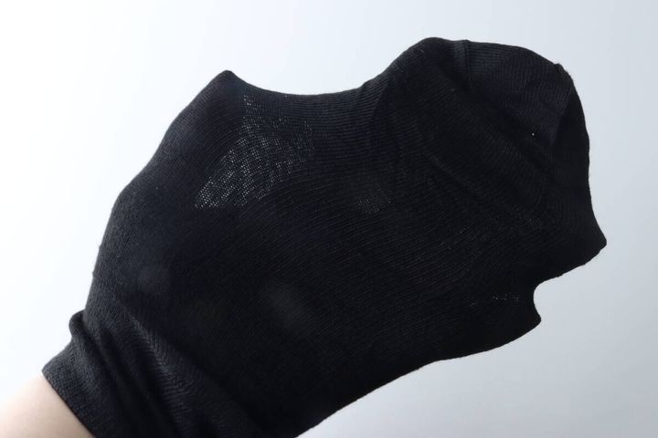 女性の手が黒いショート丈ソックスをはめて伸び具合を確認している様子