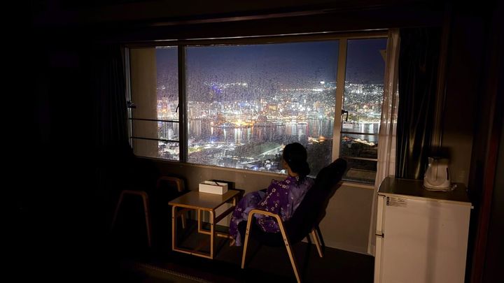 「大江戸温泉Premium 長崎ホテル清風」客室「スーペリア和室12畳」で椅子に座り夜景を眺める浴衣姿の女性