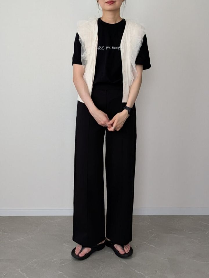 黒Tシャツと黒ストレートパンツに白チュールカーディガンを羽織った女性