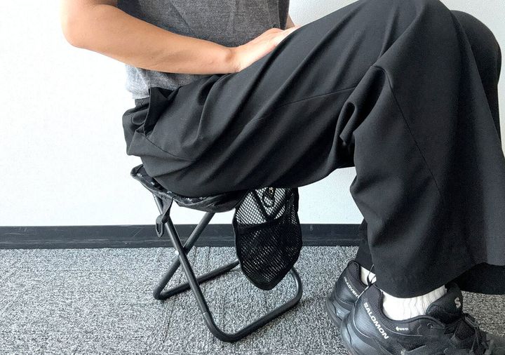 黒いパンツを履いた人がモンスターハンターの折りたたみイスに座っている