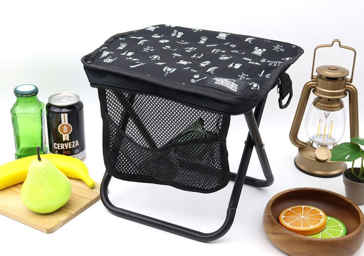 黒い折りたたみイスの周りに飲み物、果物、ランタンが置かれている