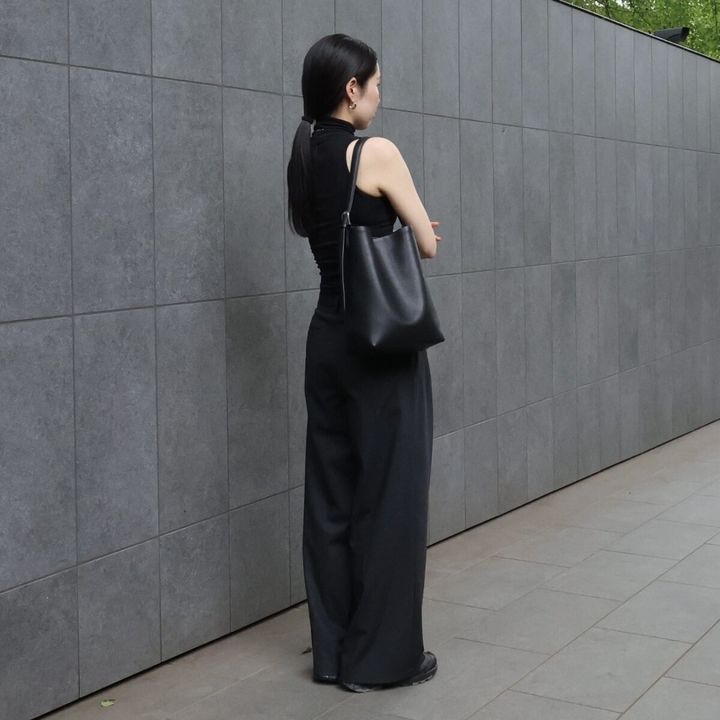 黒いノースリーブとワイドパンツを着用し、後ろを向く女性の全身