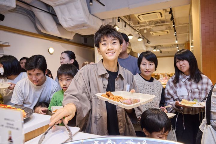 唐揚げやパスタを選ぶ少年と参加者たち