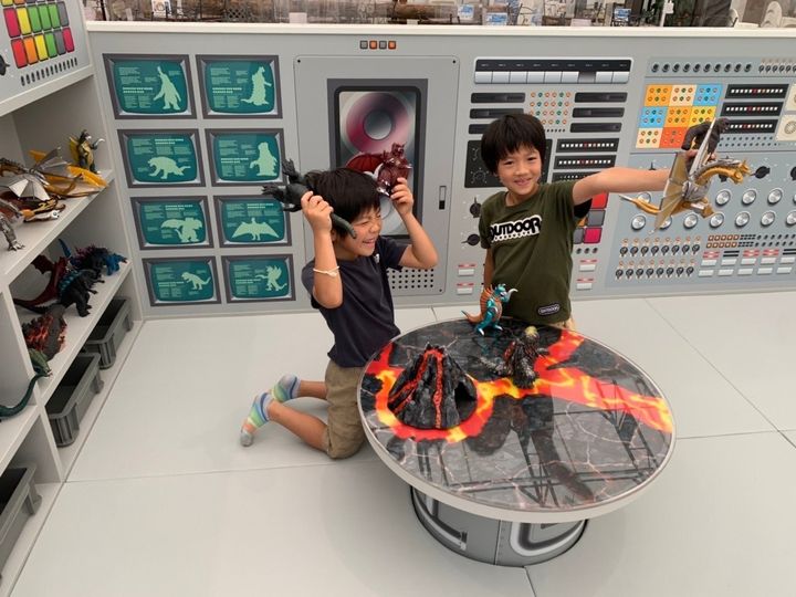 怪獣フィギュアで遊ぶ子どもたちと並ぶグッズ