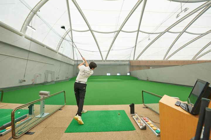 屋内ゴルフ練習場でスイングする様子