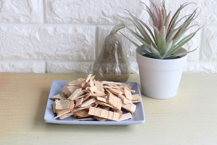 ウッドチップが盛られた皿と植物、ガラスのオブジェが並ぶインテリア