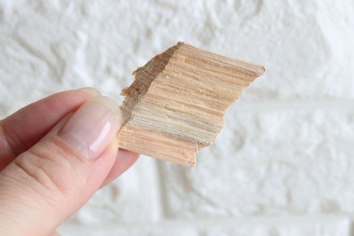 女性の指がヒノキのウッドチップを一つ摘まんでいる
