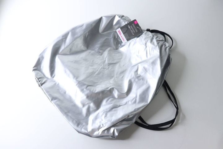 シルバーの巾着ナップサックが斜めから置かれ、商品タグが見える