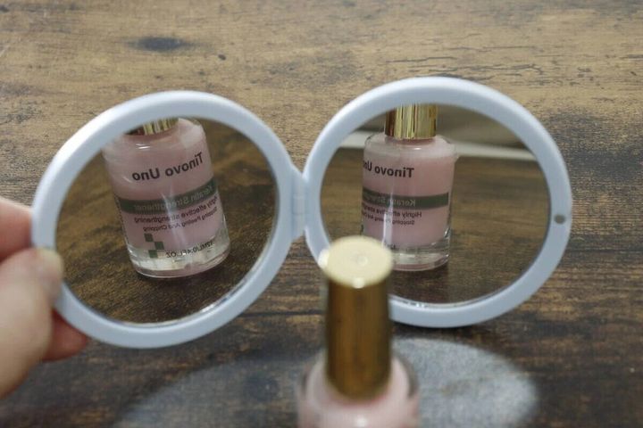 開いたルーレット付きミラーにネイルボトルが映り込む