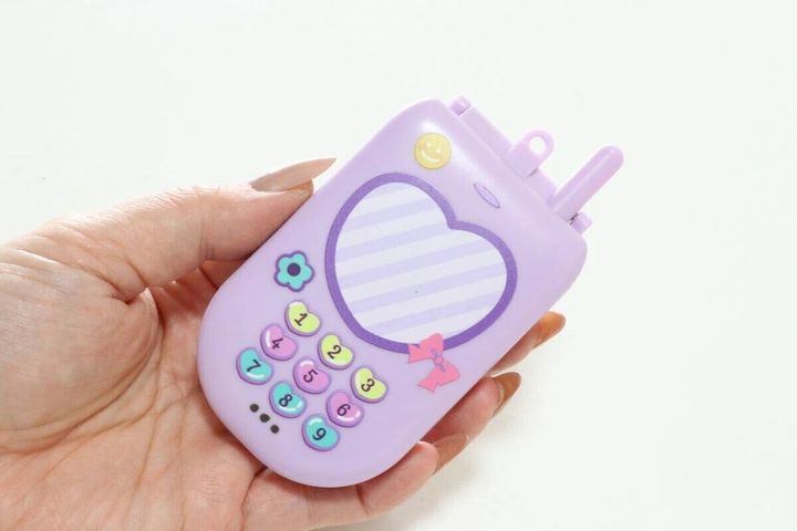 女性の手のひらに乗せられた紫色のガラケー型コンパクトミラー