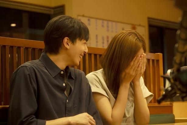【写真を見る】飲食店で取材を受けながら顔を覆って照れ笑いをする和とそれを見守る将一 [c]遠藤和／小学館 [c]2026「ママがもうこの世界にいなくても」製作委員会