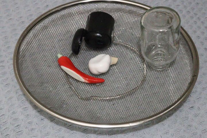 ステンレス製の浅型ザルに小瓶や調味料入れ、唐辛子などが置かれている
