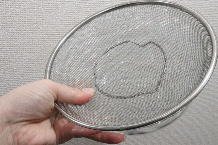 左手で浅型ザルを持ち、水が流れ落ちる様子