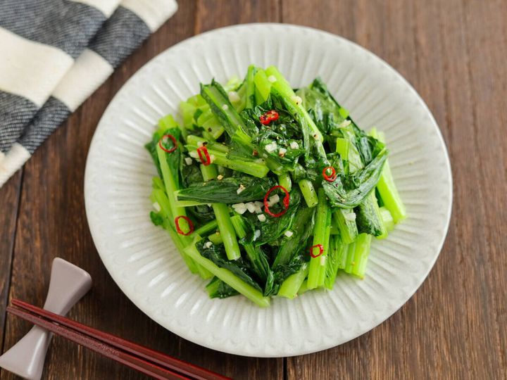 白い皿に盛り付けられた小松菜のペペロンチーノ風炒めと箸の俯瞰