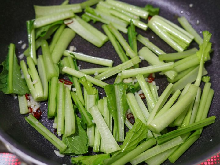 フライパンで小松菜の茎の部分を炒めている様子