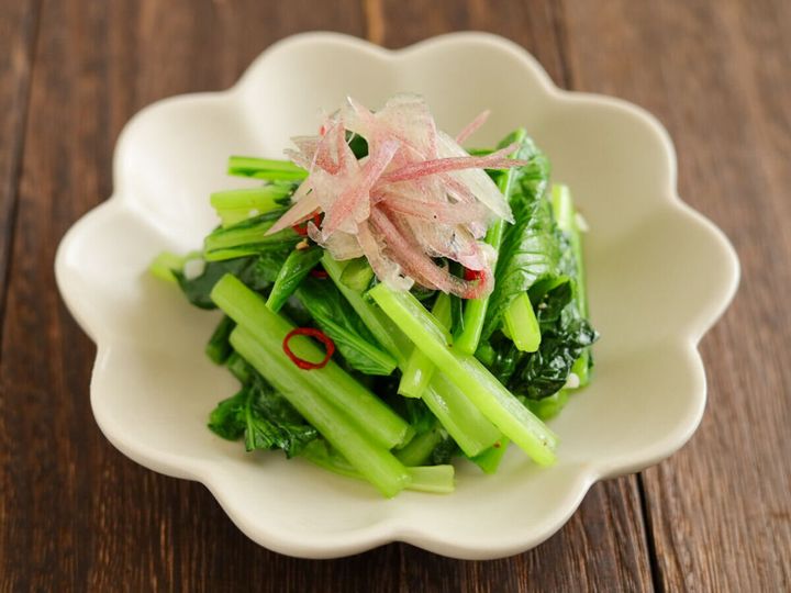 白い花形の皿に千切りみょうががトッピングされた小松菜のペペロンチーノ風炒め