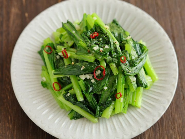 白い皿に盛り付けられた小松菜のペペロンチーノ風炒め