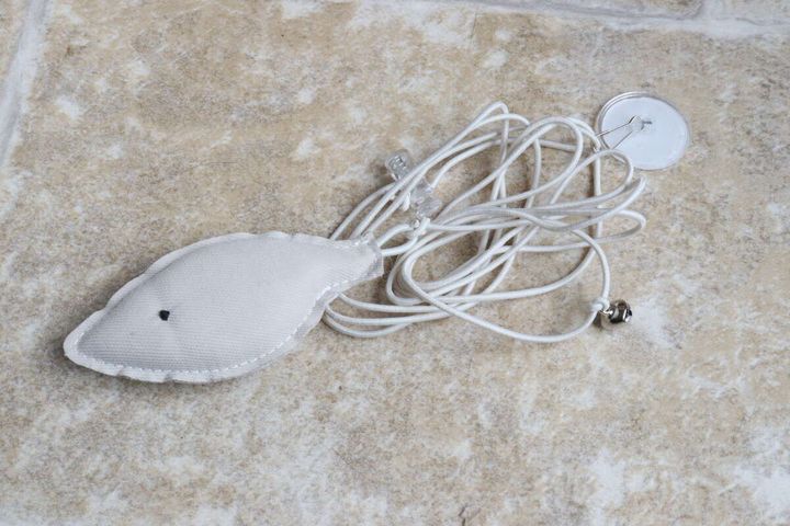 白い魚型マスコットと絡まった白いゴム紐、鈴が付いたダイソー猫じゃらしの全体像