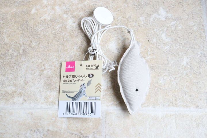 ダイソーのセルフ猫じゃらし（魚）のパッケージと商品全体が床に置かれている