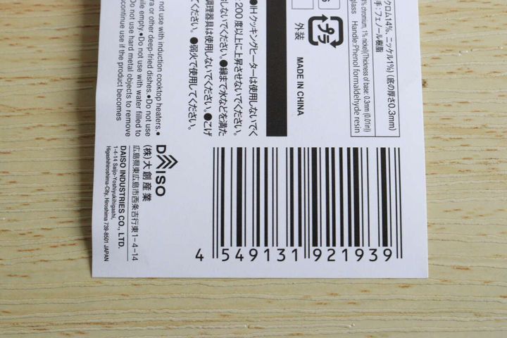 ステンレス鍋の底に貼られた商品ラベルのバーコードと注意書きのアップ