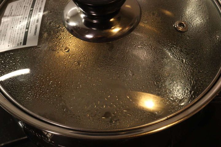 ガラス蓋の内側に水滴がつき、鍋の中の液体が沸騰している様子