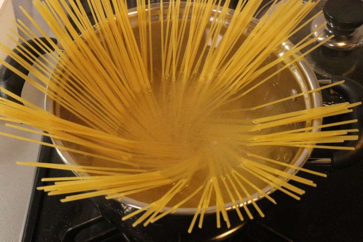 沸騰した鍋の中にパスタが投入され、茹でられている俯瞰写真