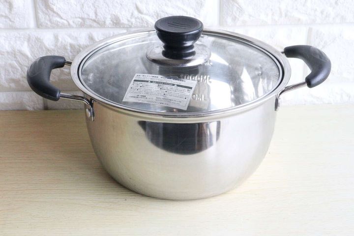 ビニールを剥がした状態のステンレス鍋が木製のテーブルに置かれている