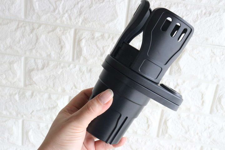 女性が黒いダイソーの2IN1車載ドリンクホルダーを手に持っている