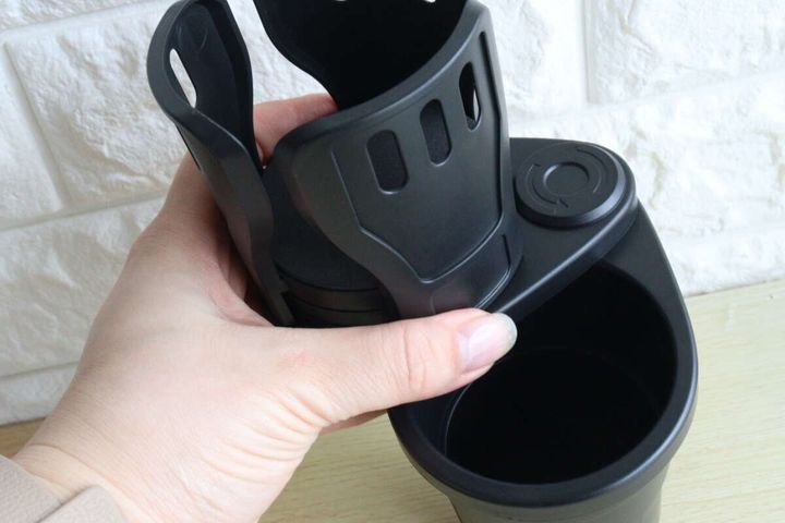 女性が2IN1車載ドリンクホルダーの上段をスライドさせている様子