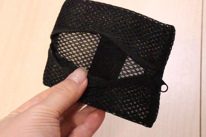 ポーチのファスナーを開けて内部のメッシュ素材を見せている手元