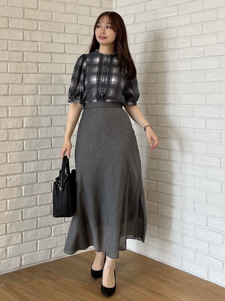 グレーのチェックブラウスとフレアスカートを着用した女性