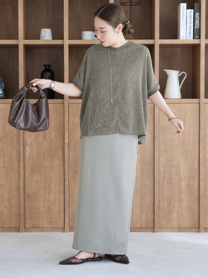 カーキのプルオーバーとグレーのナロースカートを着用した女性