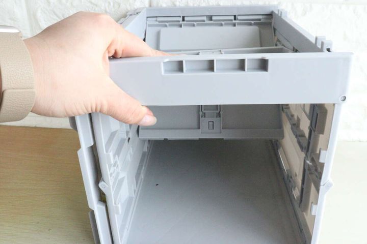 手がコンテナボックスの側面を起こして組み立てている様子
