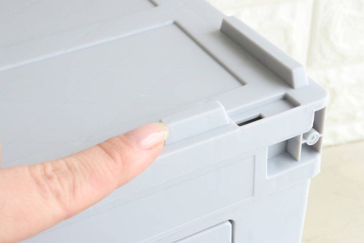 指がコンテナボックスのフタ部分にあるロック機構を指している