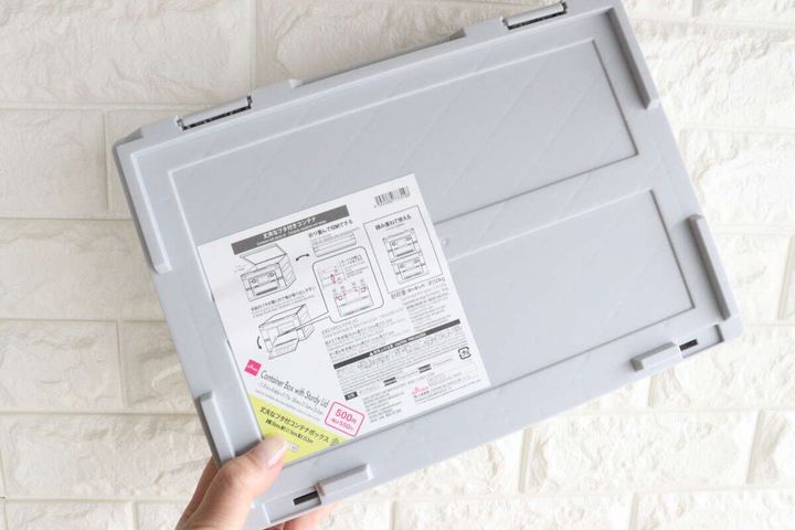 手で持ったグレーのコンテナボックスの裏面、商品情報シールが見える