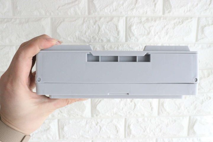 折りたたんだ状態のコンテナボックスを横から見た様子、手で持っている