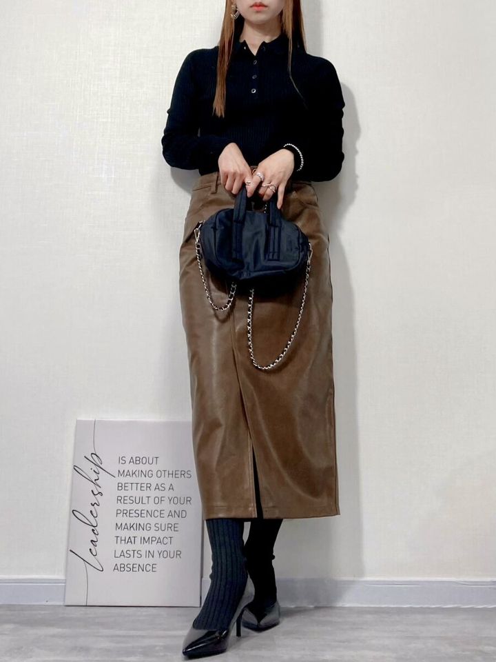 黒のポロニットとブラウンのレザー調スカートを着用した女性の全身コーデ