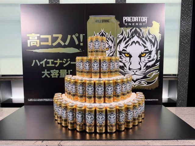 「高コスパ！ハイエナジー！大容量！」のパネル前にタワー状に積まれたゴールドの『プレデターエナジー』缶