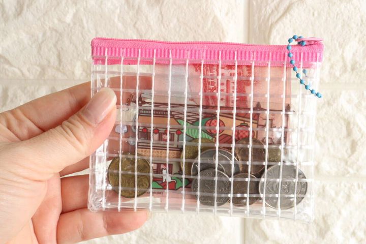 女性の手がミニメッシュポーチを持ち、中に紙幣と複数の硬貨が入っている様子