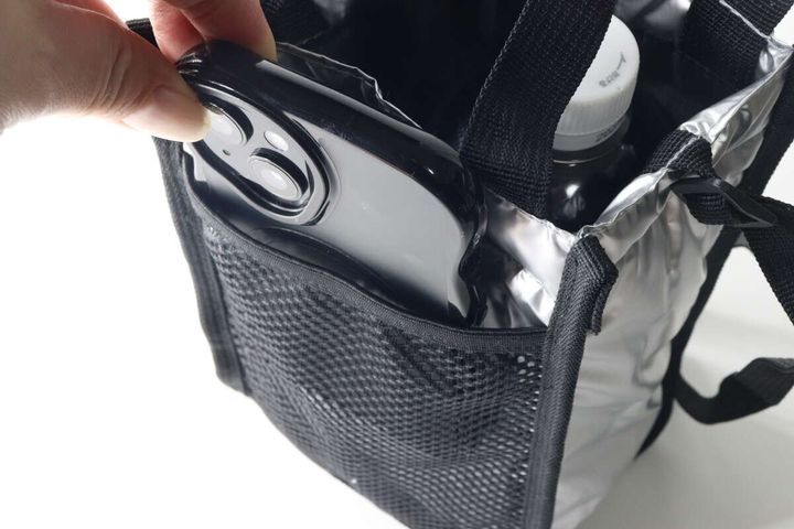 シルバーと黒のショルダーバッグのメッシュポケットにスマホを入れている手元